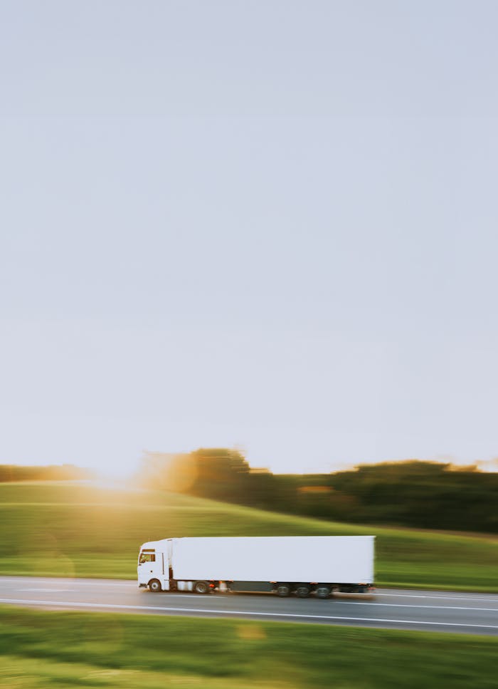 ours-journey White cargo truck speeding through Vitebsk countryside at sunrise, symbolizing transportation and logistics.